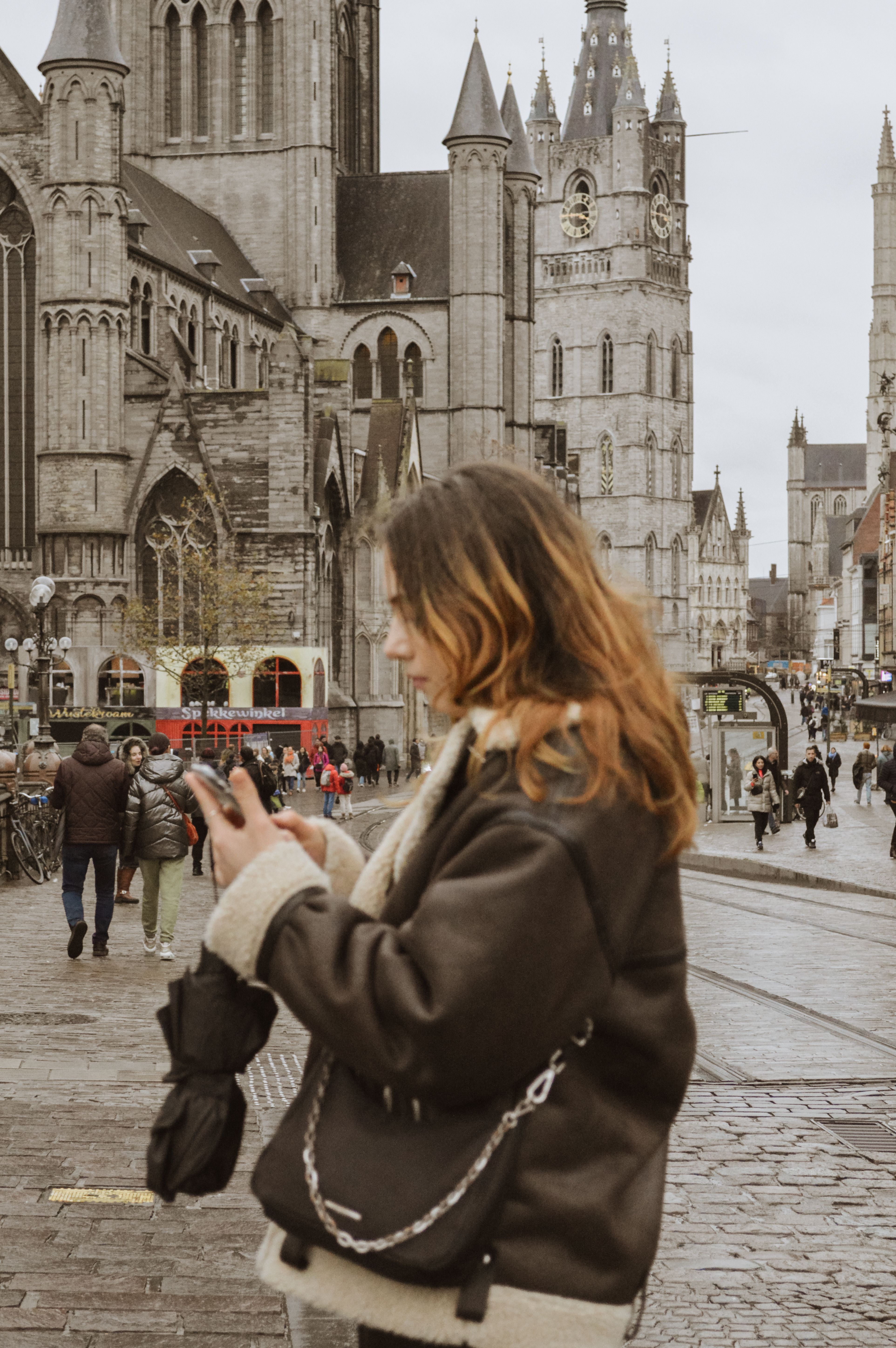 A woman in Ghent, Belgium, using a phone near St. Nicholas' Church.