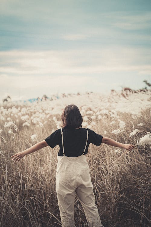 Back View of a Woman with Spread Arms on a Field 