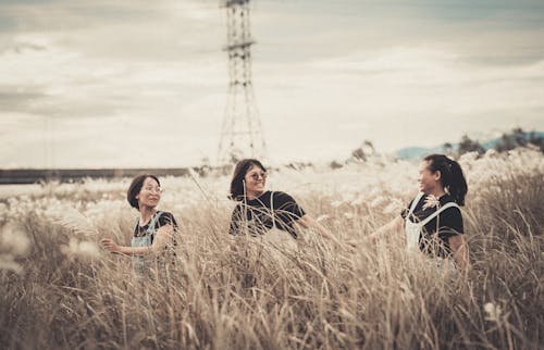 Three Women Walking on Brown Grass Field