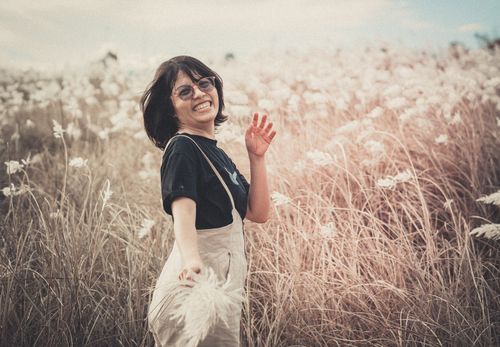 Free A smiling woman in a black shirt enjoys the outdoors in a wheat field. Stock Photo