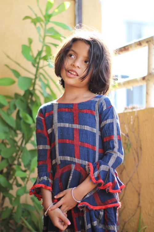 Free Charming portrait of a young girl in a plaid dress enjoying the outdoors. Stock Photo