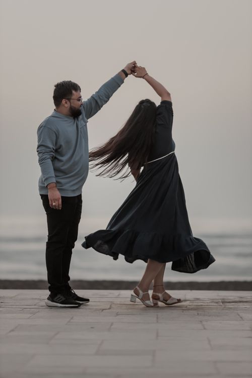 Free A couple enjoys a romantic dance by the seaside, capturing a moment of love and spontaneity. Stock Photo