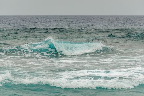 Free A calming ocean wave breaking on the sea surface under a cloudy sky, capturing the tranquility of nature. Stock Photo