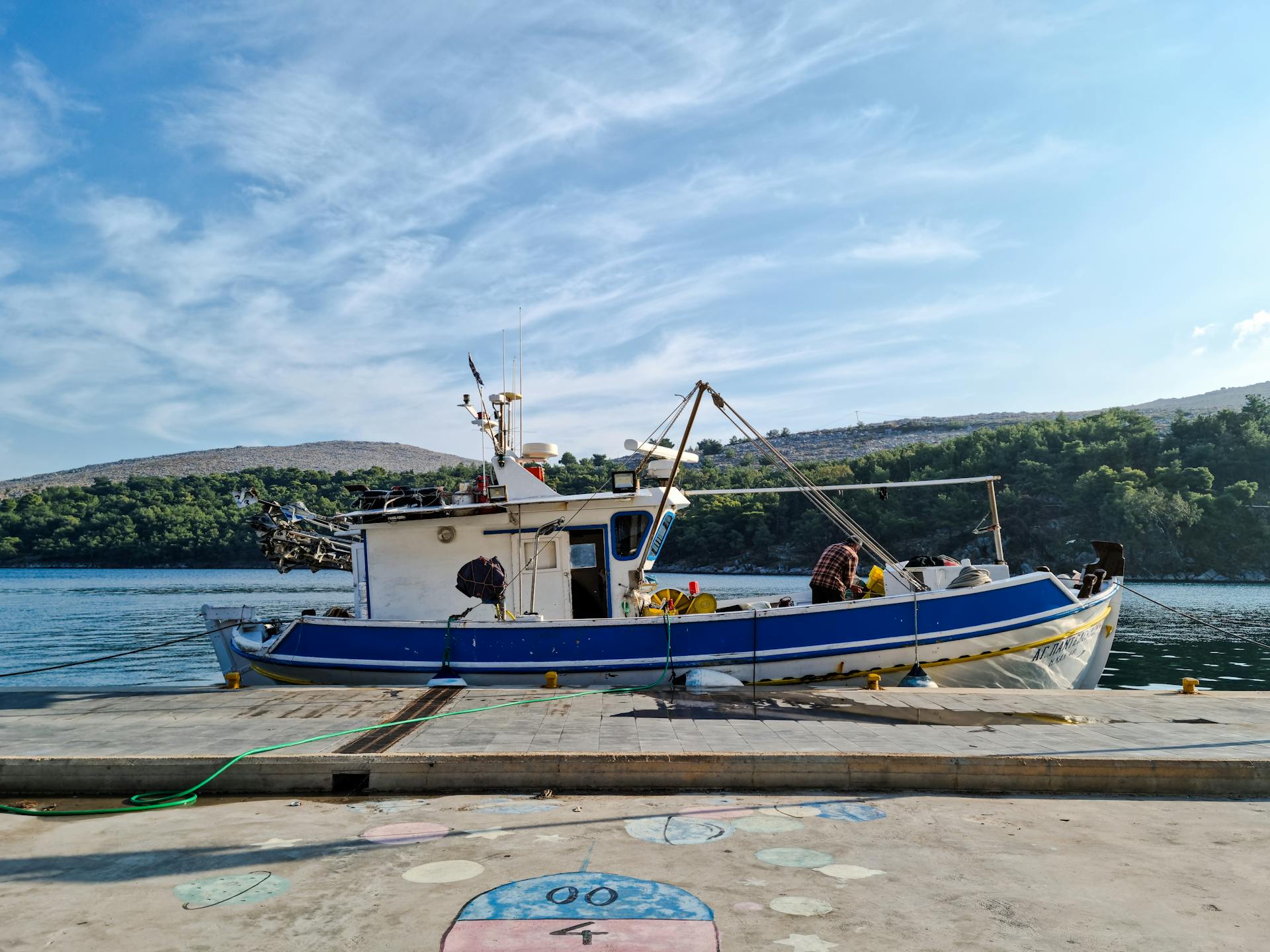 A colorful fishing boat moored in a picturesque Greek harbor under a clear blue sky.