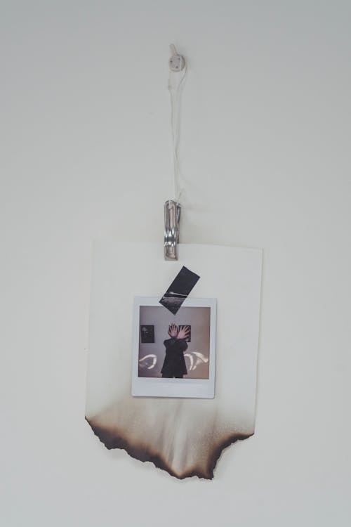 Installation of a Polaroid Photo with Burned Passepartout Hanging on a White Wall