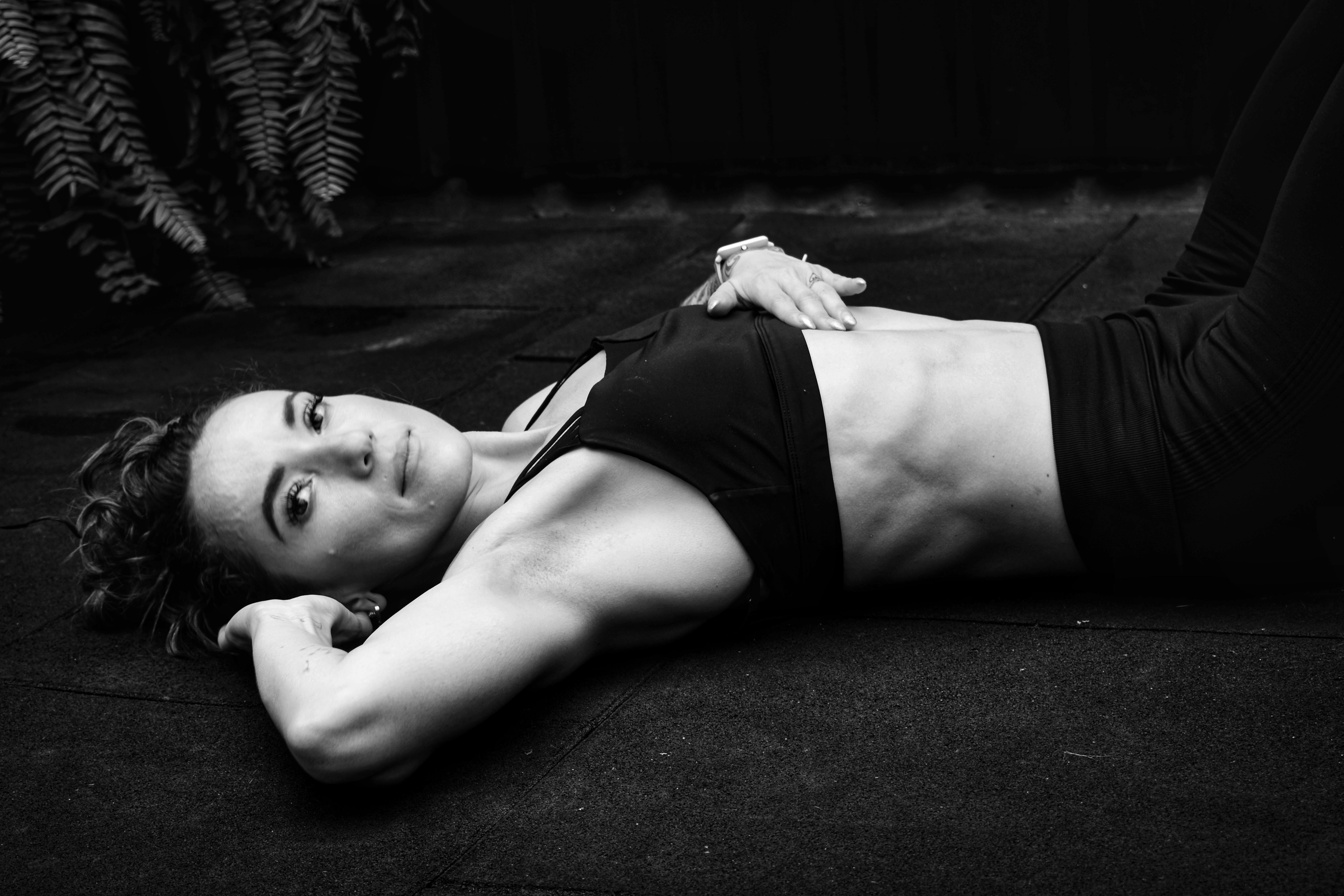 A woman in a sports bra lying on the floor in a contemplative pose.