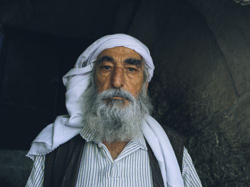 Free A compelling portrait of a senior man in traditional attire, featuring a striking beard and headwear. Stock Photo