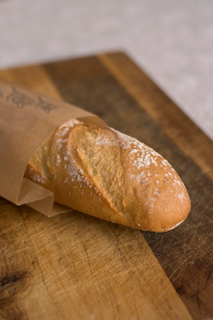 Photo Of A Loaf Of Bread In A Paper Bag On A Breadboard