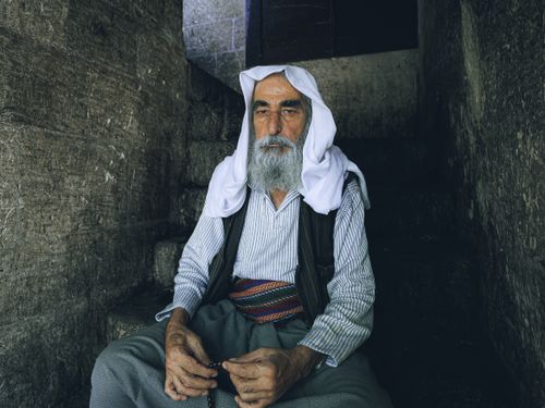 Free Senior man with white headscarf sitting on stone steps, exuding peace and spirituality. Stock Photo