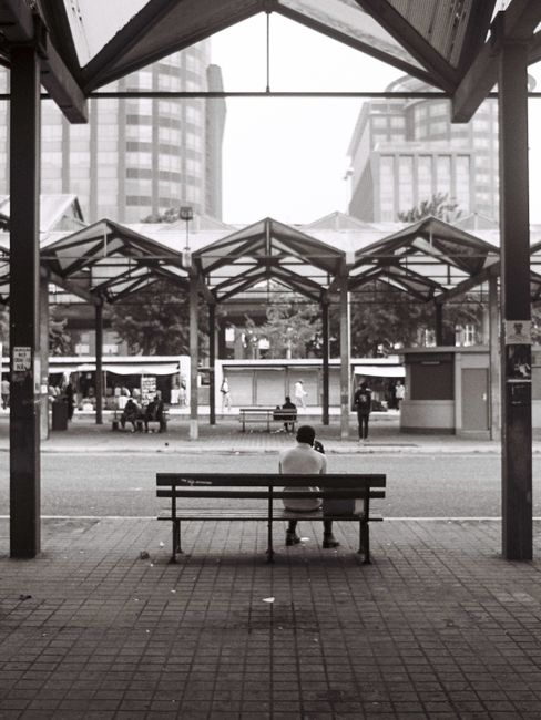 A traveler sits on a bench in a Lisbon terminal, embracing modern architecture.