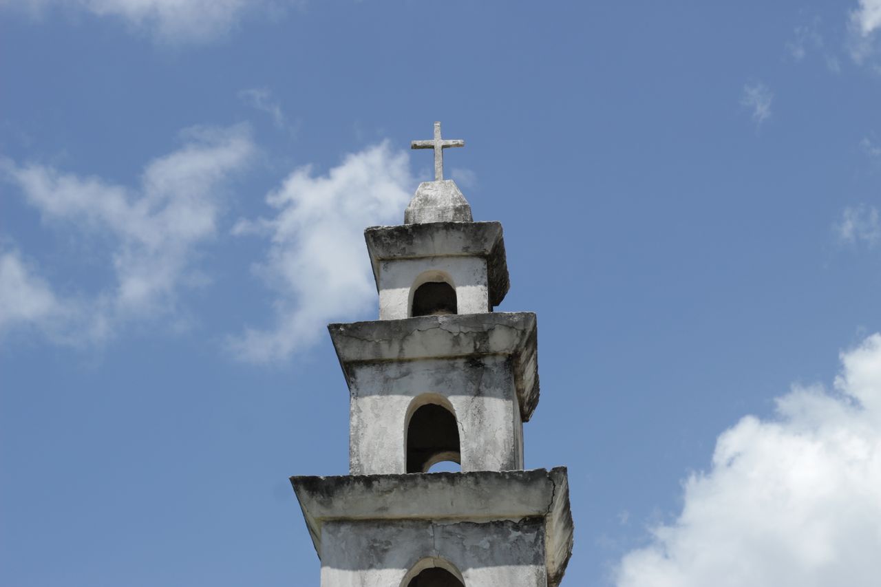 a historic church tower in dzemul mexico with a prominent stone cross