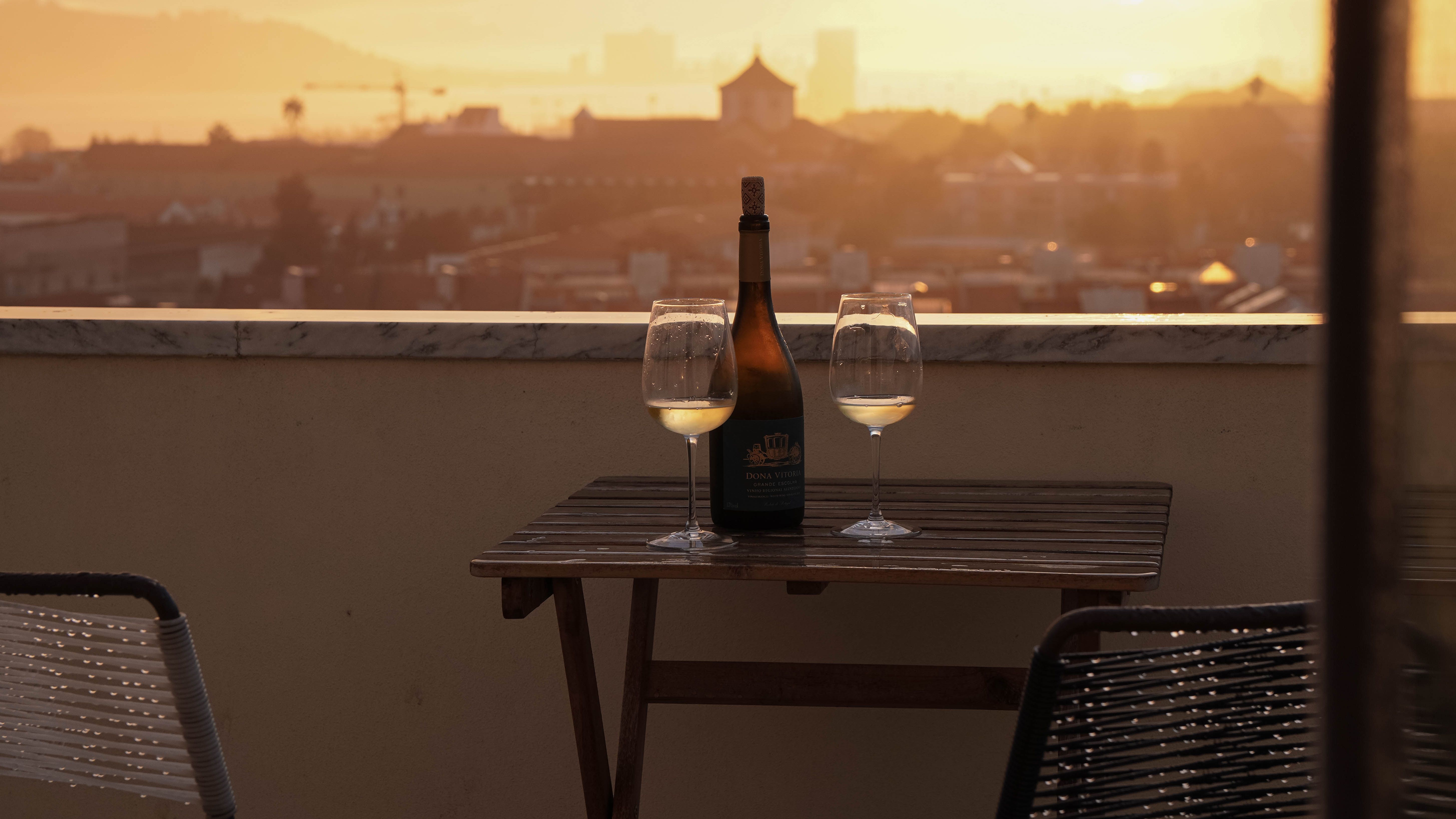Enjoy a glass of wine on a Lisbon rooftop at sunset, capturing a serene and picturesque view. Enjoy a glass of wine on a Lisbon rooftop at sunset, capturing a serene and picturesque view.