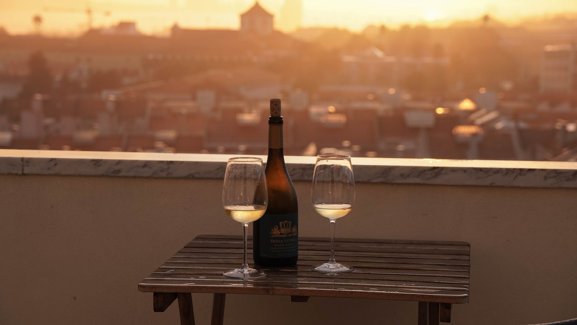 Chilled white wine poured into a glass on a Bangkok rooftop, condensation on the bottle