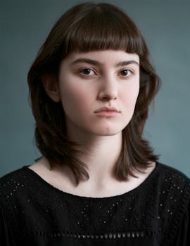 A young woman with brown hair poses against a gray background in Karaj, Iran.
