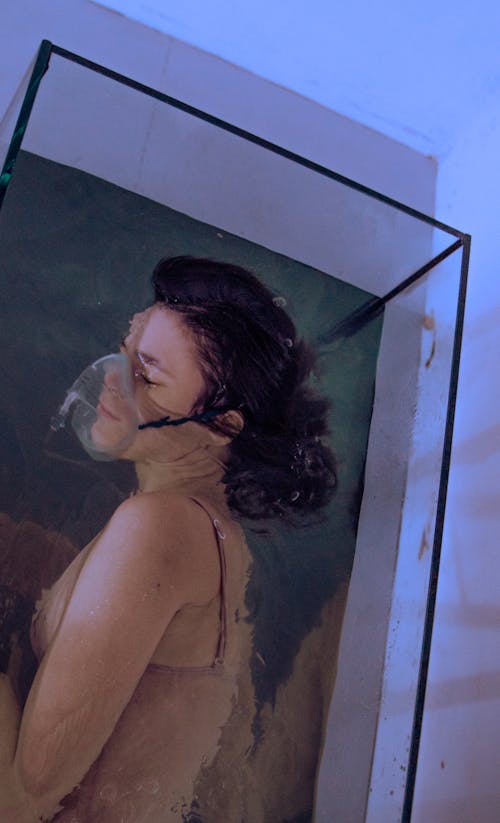 Woman Wearing an Oxygen Mask Submerging in an Aquarium
