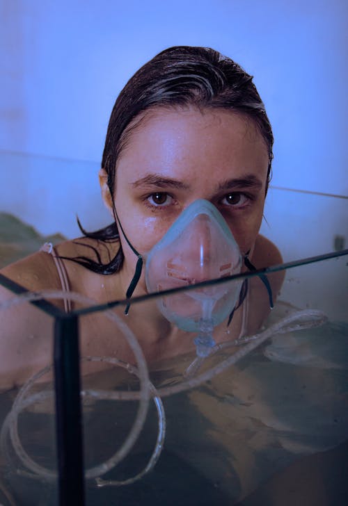 Woman Wearing an Oxygen Mask Submerging in an Aquarium