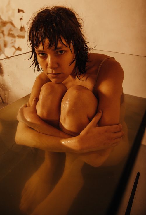 Free A woman sits introspectively in a warm, tranquil bathtub setting, creating a serene mood. Stock Photo
