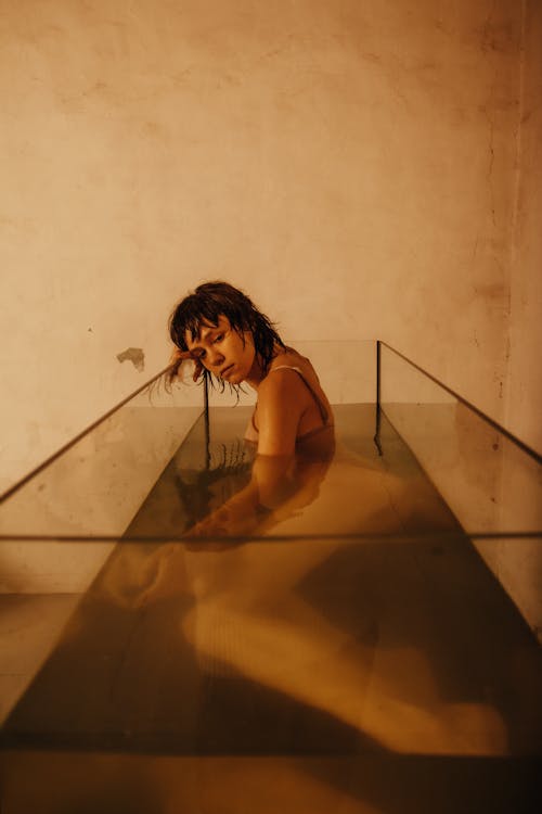 Posed Photo of a Young Woman Lying in a Glass Tank Filled with Water