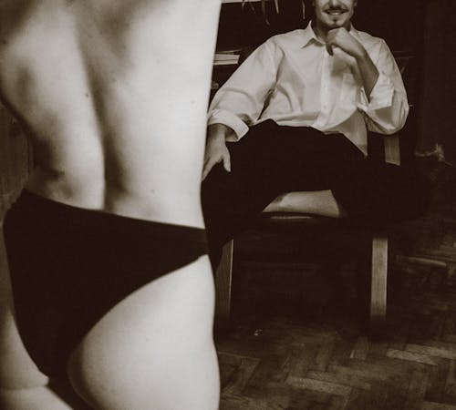 Back View of a Shirtless Woman, and Man on a Chair Starring