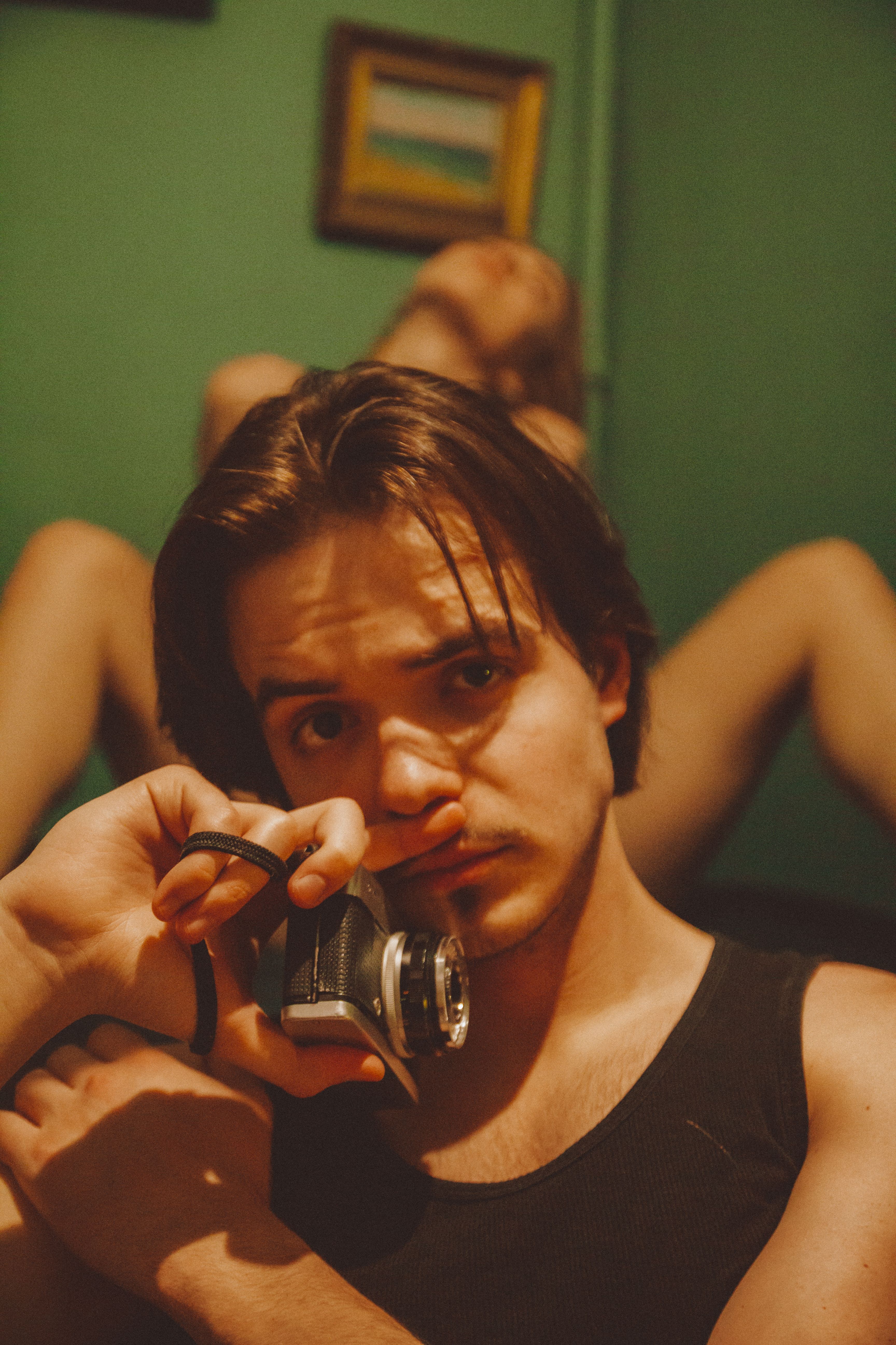 Close-up portrait of a man holding a vintage camera with a thoughtful expression.