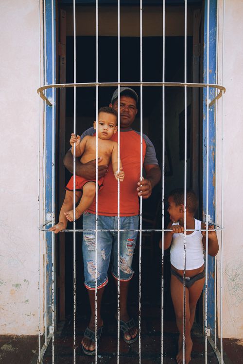 Free A father and his two young sons stand behind window bars, conveying family bonds. Stock Photo