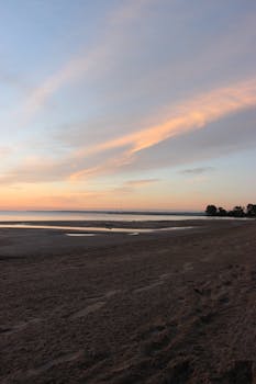 A peaceful sunrise view over Burlington Beach with serene sandy shoreline and colorful skies.
