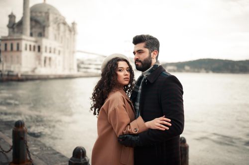Free A fashionable couple embracing by the sea in Istanbul with Ortaköy Mosque in the background. Stock Photo