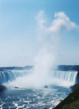 Magnificent view of Niagara Falls with mist and boat in Ontario, Canada.