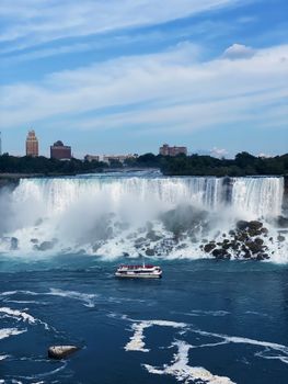 A scenic view of Niagara Falls with a tour boat on the river, capturing the majestic waterfall.