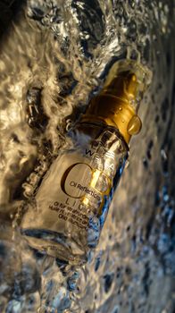 Close-up of a cosmetic vial with a dynamic water background.