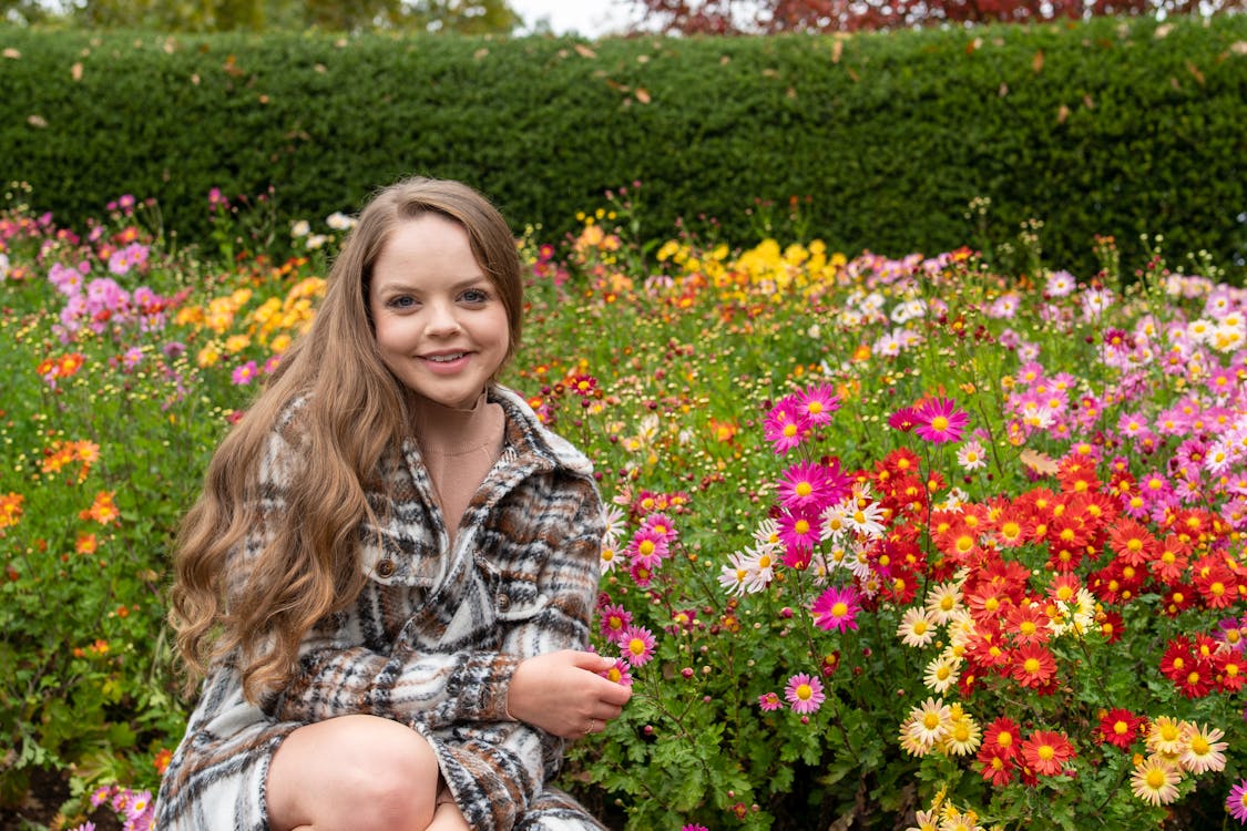 A Woman Posing Beside Blooming Flowers