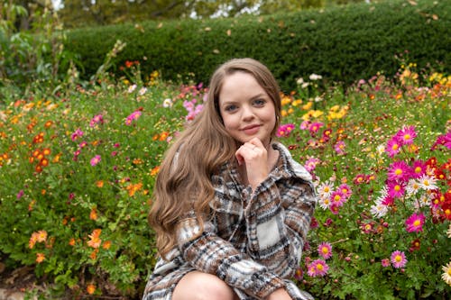 A Woman Posing Beside Blooming Flowers