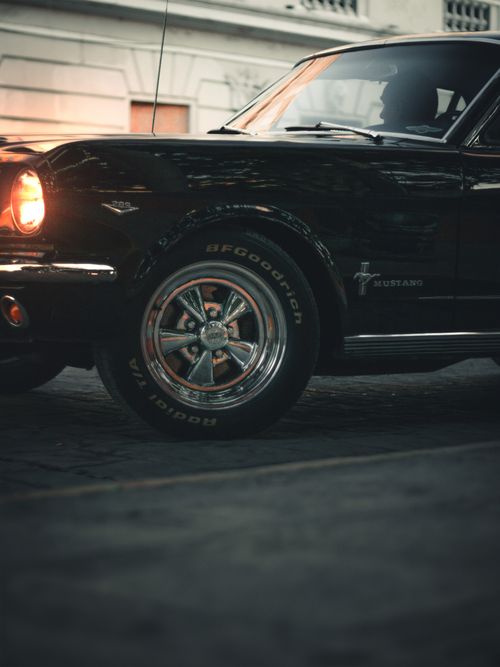 Free Classic black Ford Mustang illuminated in dusk, highlighting its vintage allure on a cobblestone road. Stock Photo