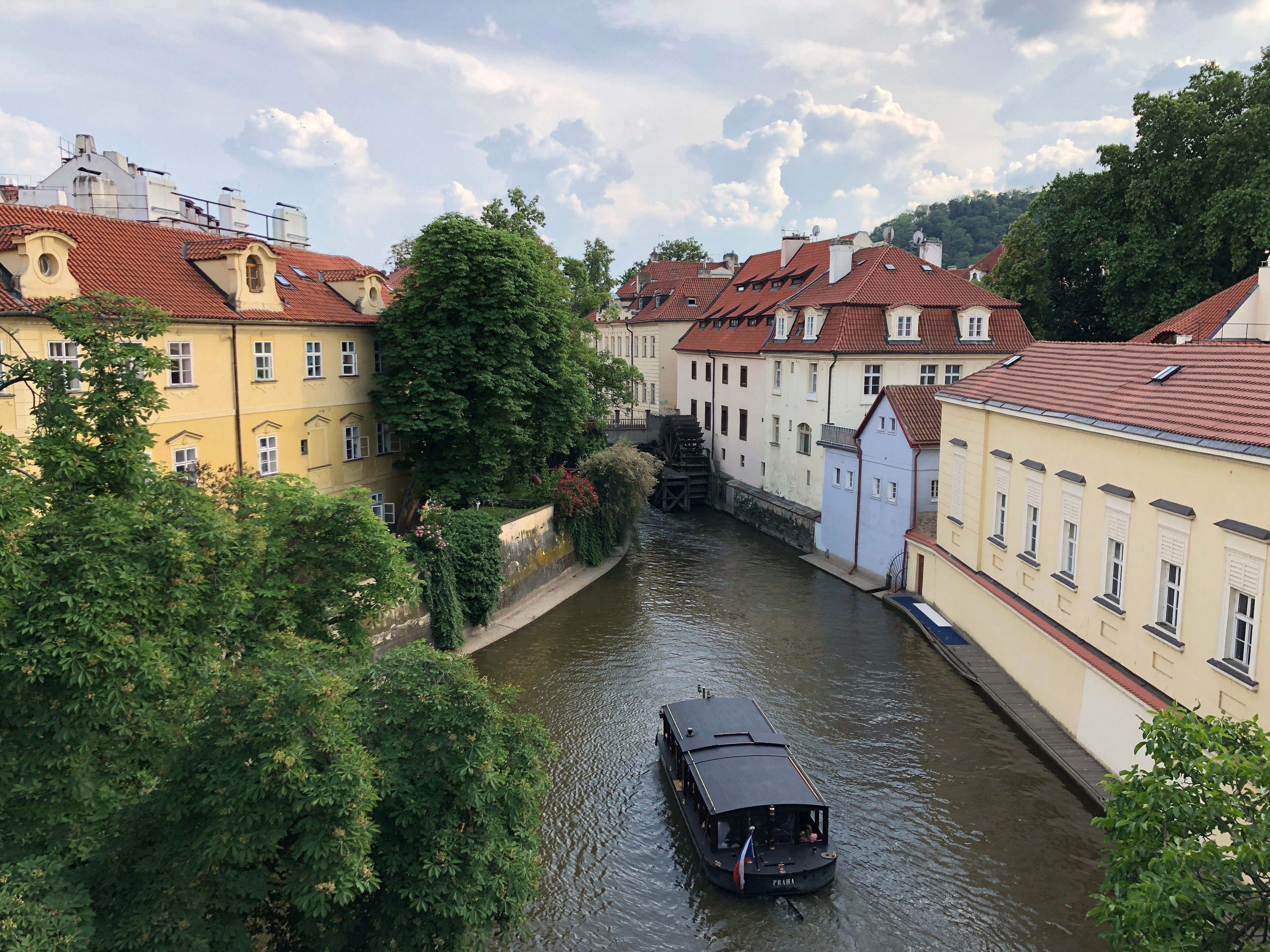 Charming buildings and a canal in Prague with a boat on a sunny day.