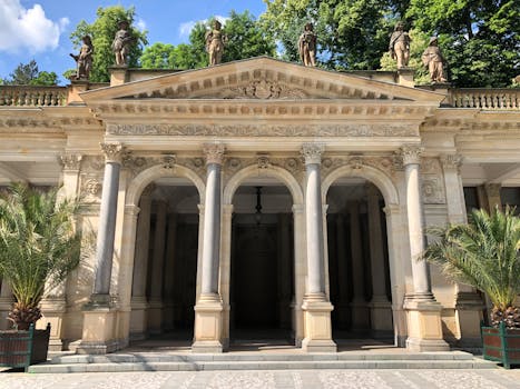 Classic Mill Colonnade in Karlovy Vary, Czechia, with ornate statues and lush greenery.
