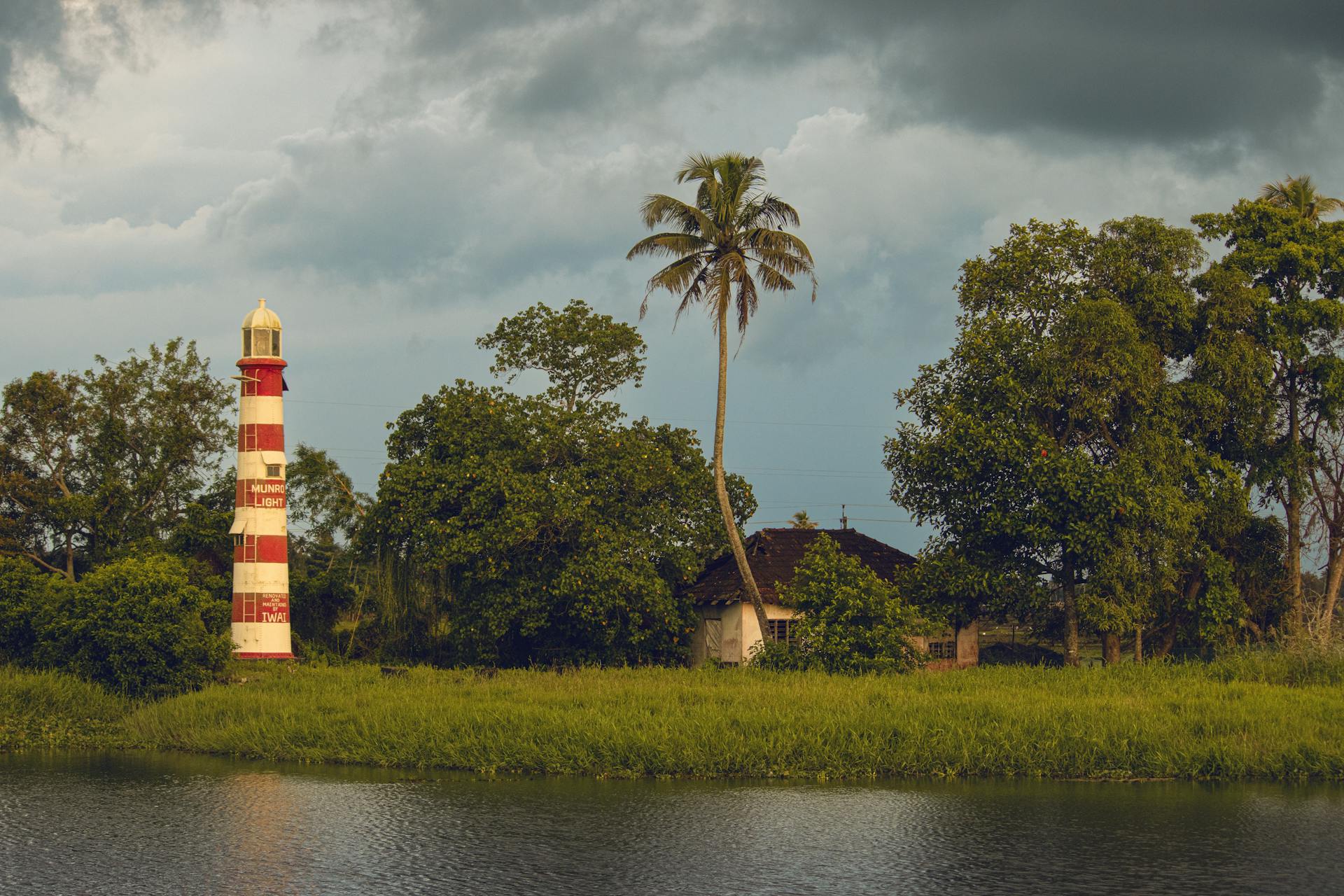 Scenic view of Munroe Lighthouse amidst greenery in Kottayam, India, under a moody sky.