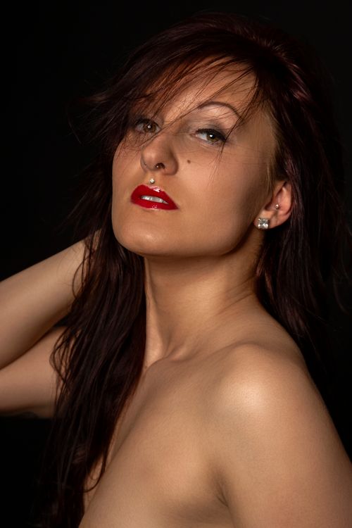Free Striking studio portrait of a woman with red lips and dark hair against a black background. Stock Photo