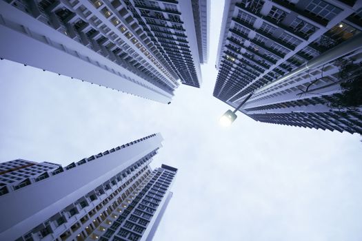 Low-angle view of towering, modern skyscrapers creating a dramatic urban skyline against a cloudy sky.