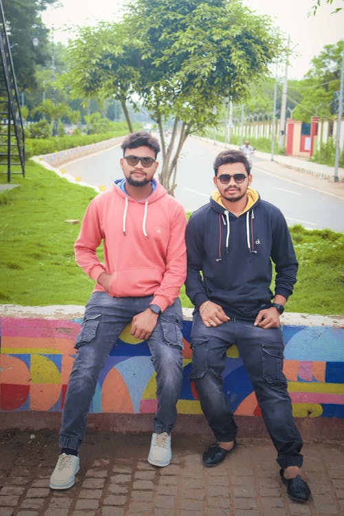 Two Brothers Sitting On Wall Besides A Highway