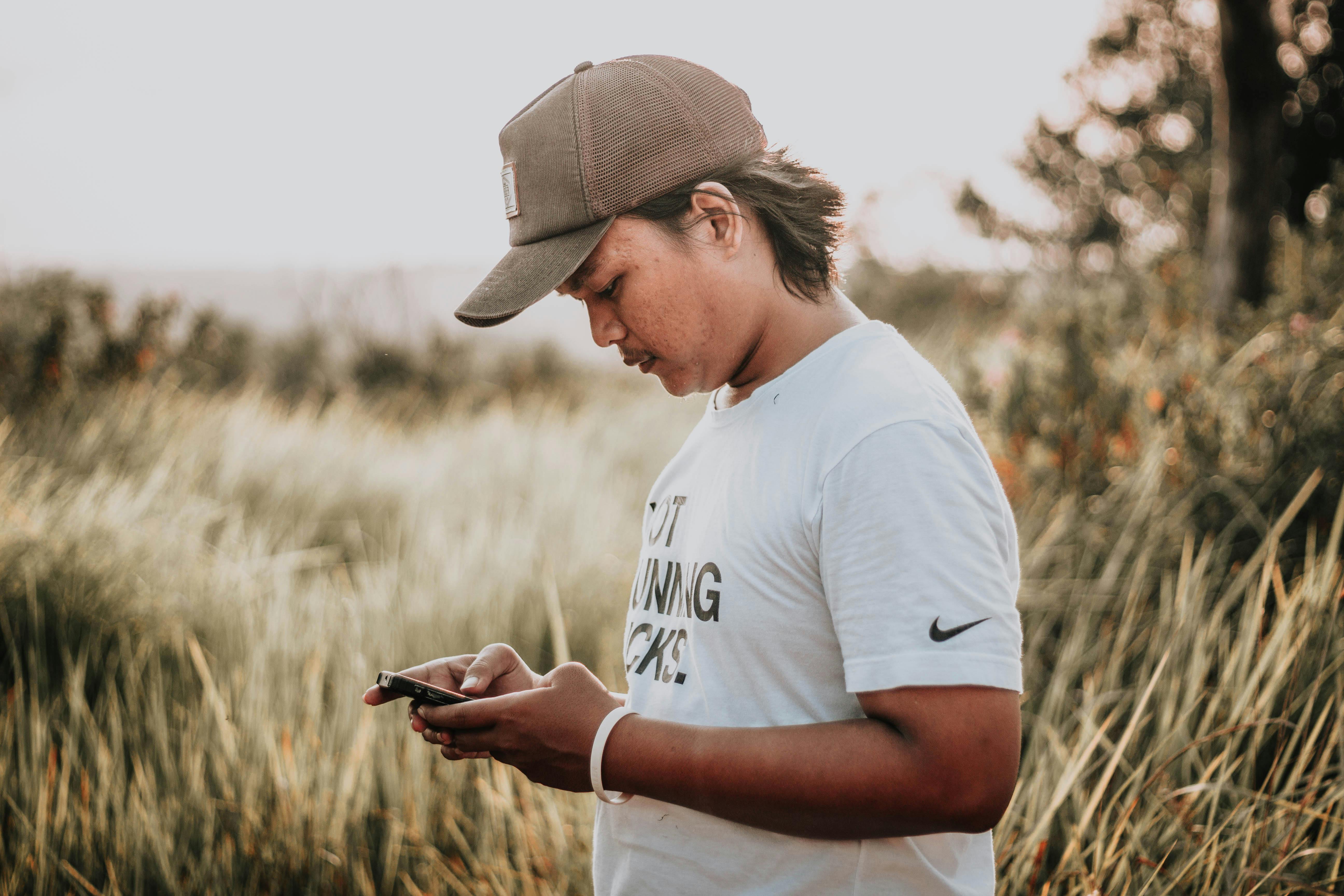 日落时分，年轻人在草地上玩手机