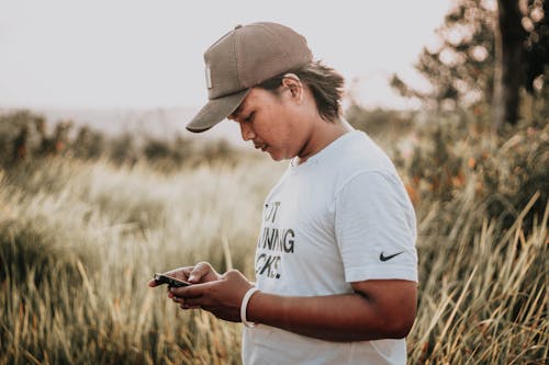 Pria Berdiri Di Lapangan Rumput Saat Menggunakan Smartphone