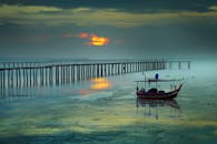 在马来西亚乔治镇，宁静的日出、船只与码头倒映在海面上，呈现出充满活力的色彩