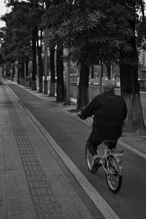 Grayscale Photo of Man Riding Bicycle