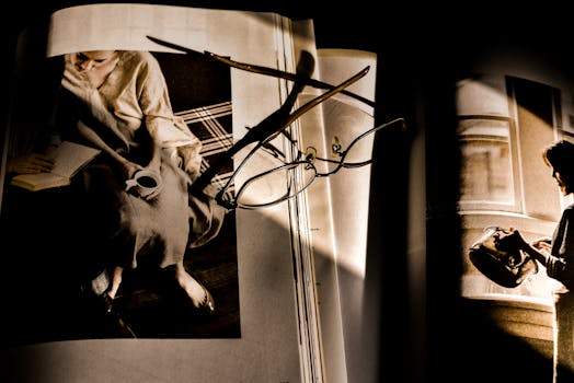 艺术镜头下的眼镜与摊开的书本，在戏剧性的照明中凸显出棕褐色调