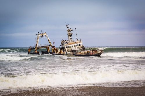 Free Rusty shipwreck stranded on the rugged coast of Swakopmund, Namibia. Stock Photo