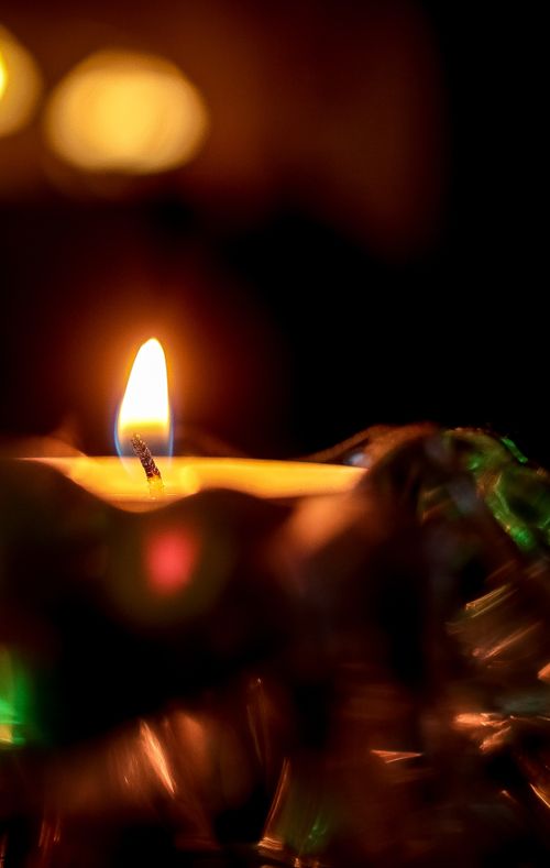 Free Close-up of a glowing candle flame creating a warm ambiance in the darkness. Stock Photo