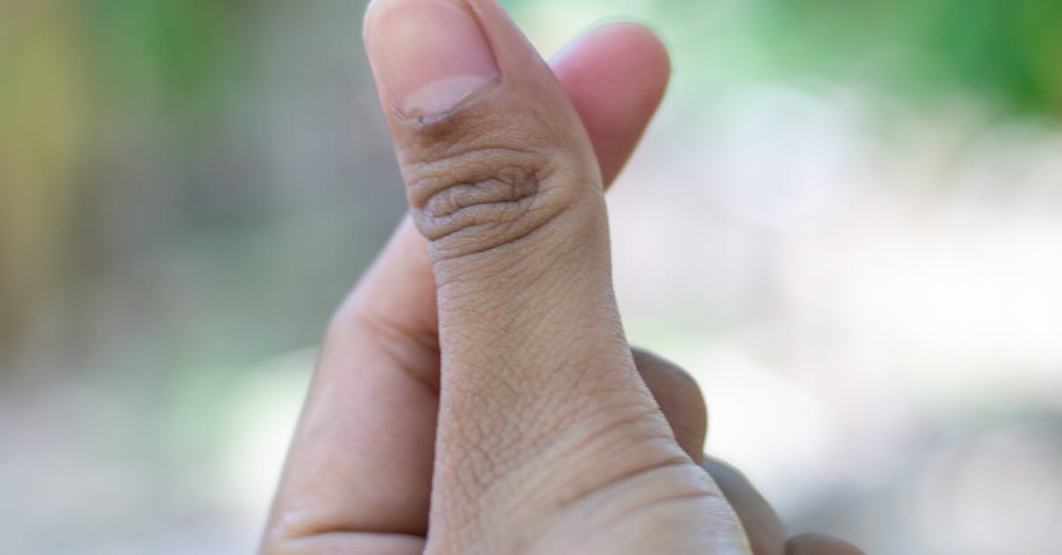 Close-up of a hand forming a heart gesture in a lush outdoor environment.