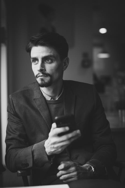 Grayscale Photography of Man Holding Smartphone