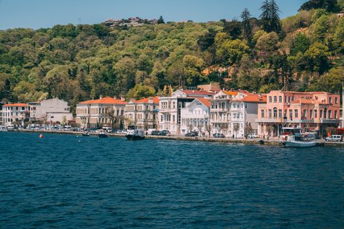 Free Charming waterfront with historic buildings and lush greenery under a clear sky. Stock Photo