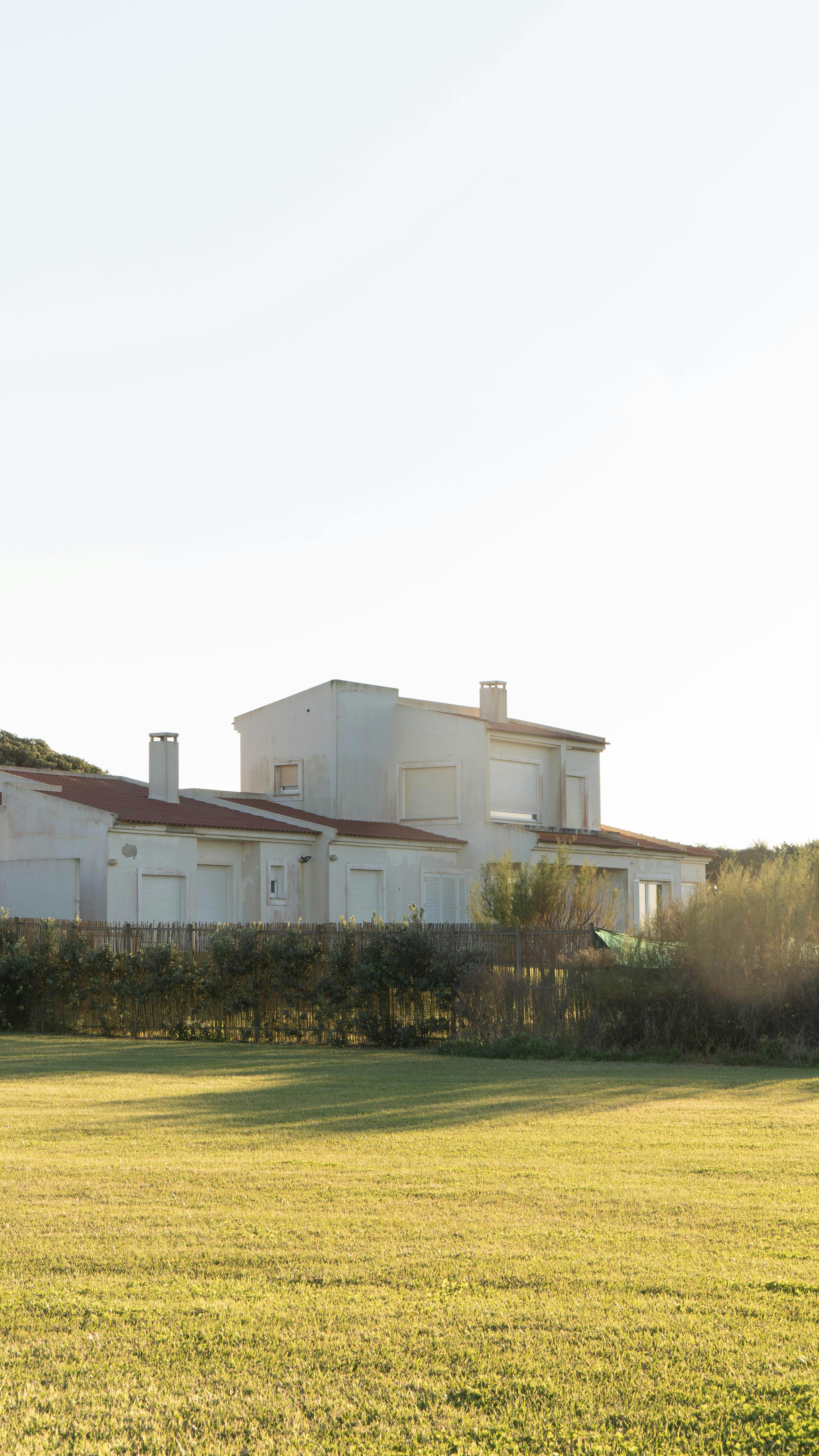 Charming white houses in Nazaré, Portugal, under clear skies, surrounded by green fields.